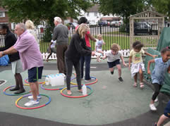 Adults standing in coloured rings on a playground while children run around them