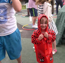 Smiling child in a red spotted coat with hood
