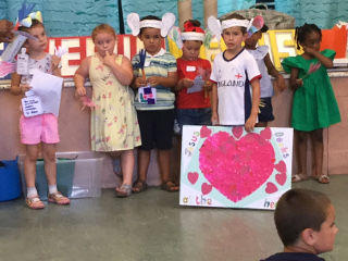 Some children wearing paper ears, one holding a poster with a heart saying 'Jesus looks at the heart'