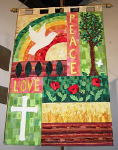Top half has 'PEACE' vertically in yellow on rose, separating on the left a white dove flying in front of a red, yellow and green rainbow and on the right a dove flying to a green tree. Lower half has on the left the word 'LOVE' in yellow on rose over a white cross on variegated light green squares, and on the right a horizontal panel with three vivid poppies with leaves on a green leafy background above a row of yellow wheat above brown earth.