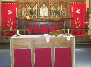 Altar with bright red curtains each side, each with a white dove flying towards the centre