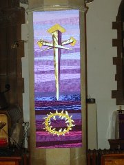 Abstract cross of three nails with golden heads above a plaited golden crown of thorns, against horizontally striped background, purple and blue at top, darkening to brown and blue stripes, then becoming brown and pink at the bottom